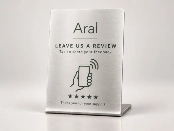 A brushed steel front-desk stand with a green crest, leave us a review and a tap mark